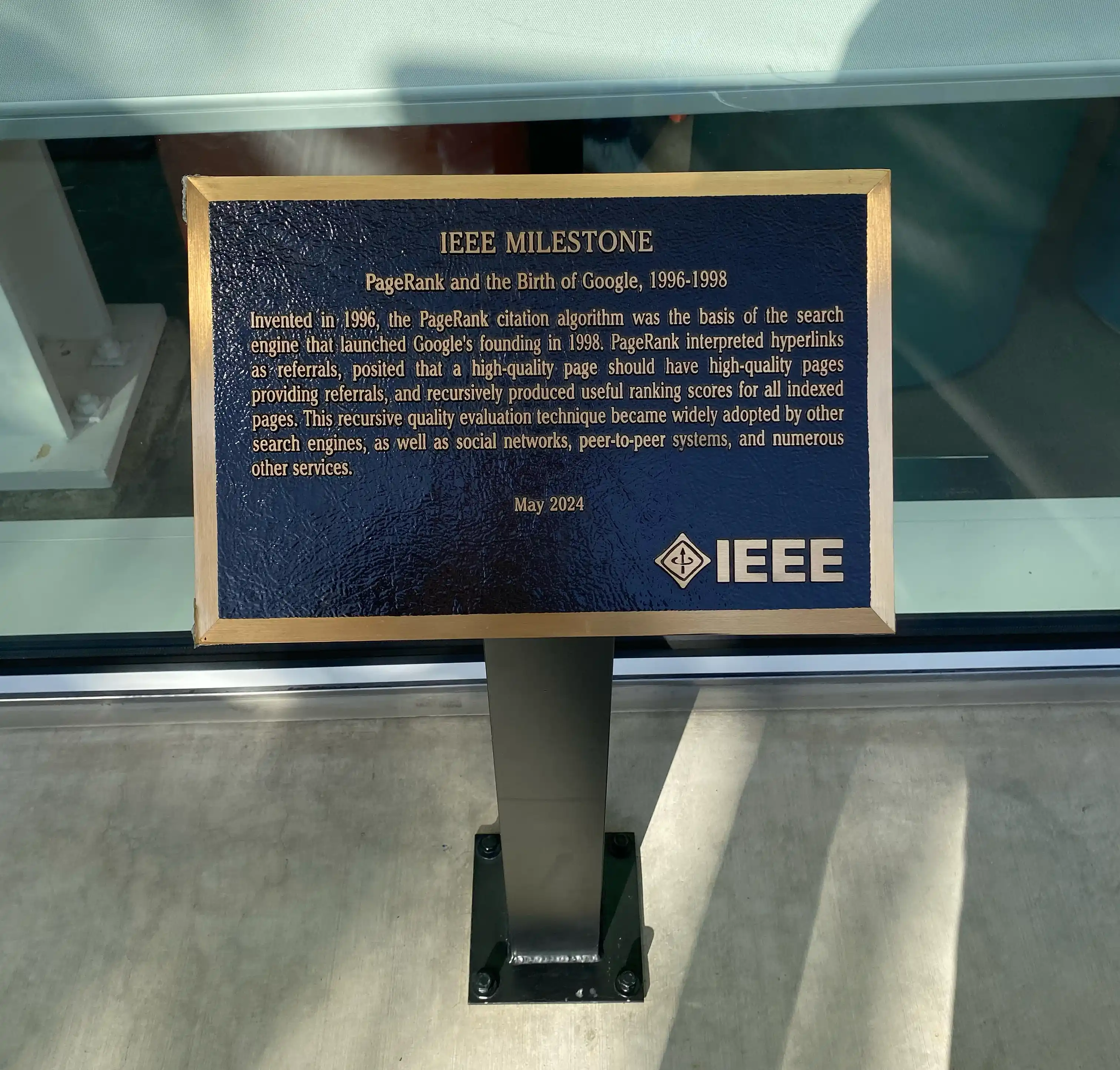 A golden-edged, bluish plaque with golden lettering. It has the title "IEEE Milestone" and a large IEEE logo, with the subtitle "PageRank and the Birth of Google, 1996-1998." The rest of the text describes the birth of search algorithms.