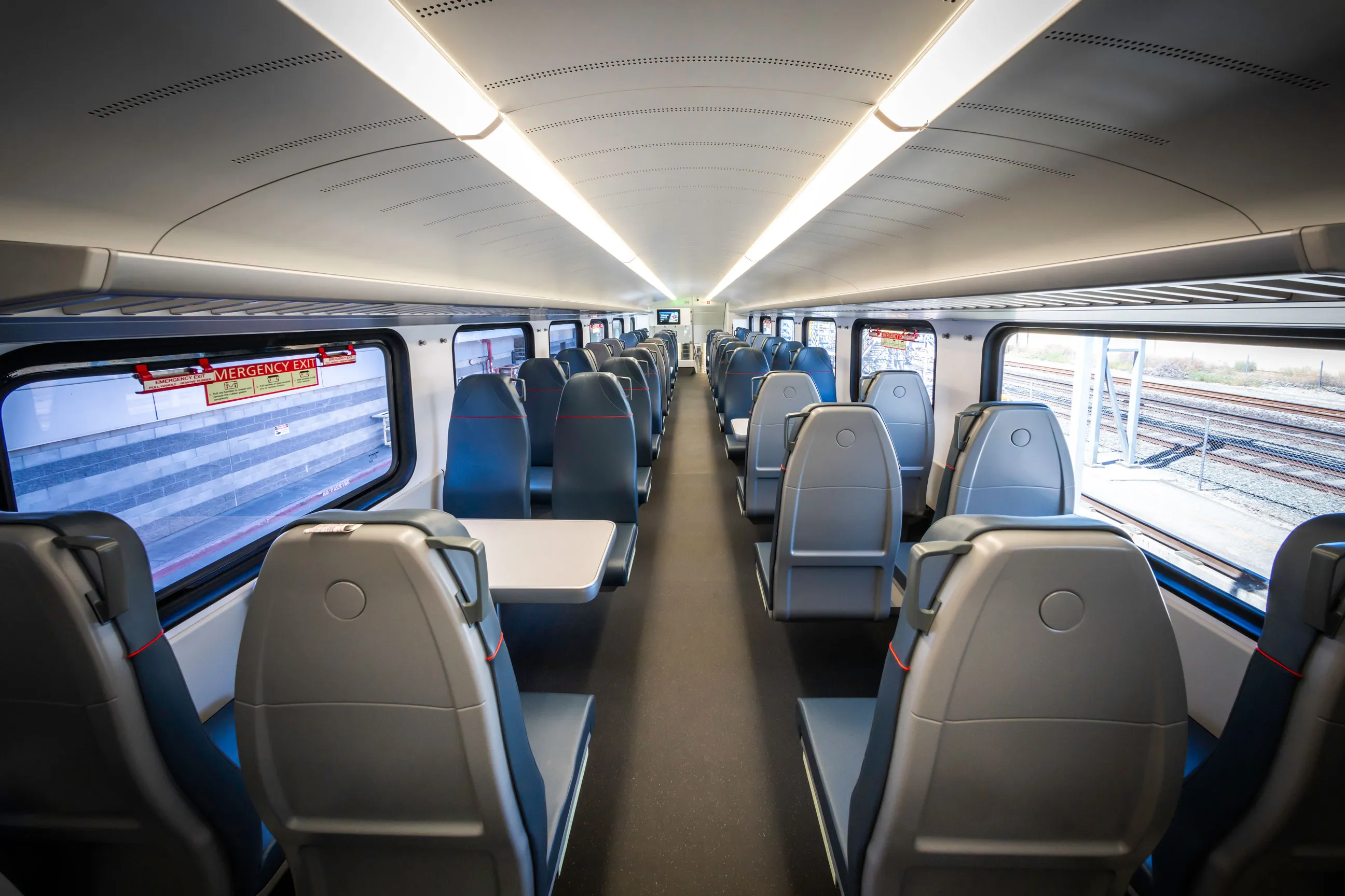 Two-person seats are arranged across an aisle, and there are also four-person table seats.