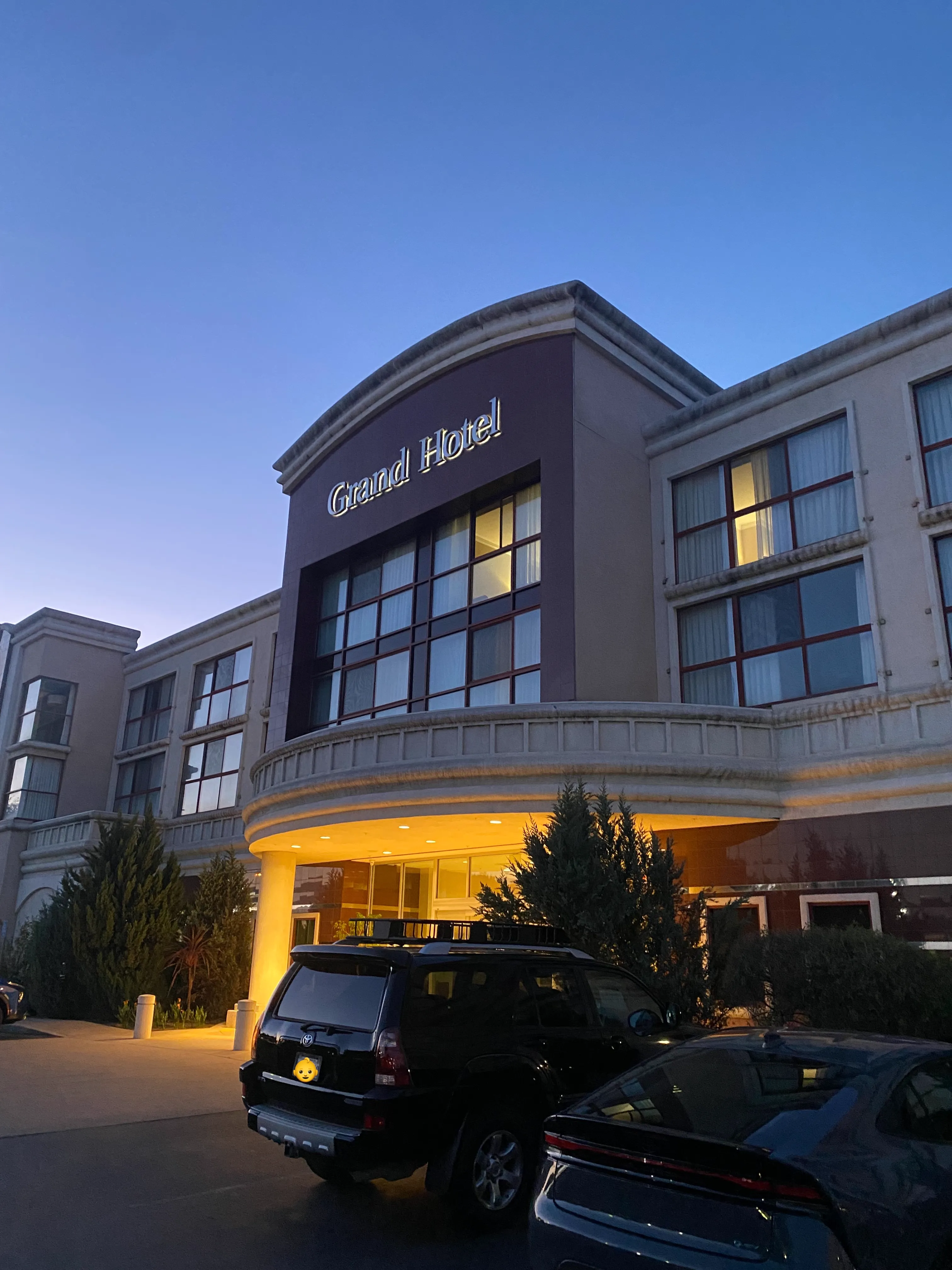 Photo of The Grand Hotel under a dusk sky, with its logo illuminated.