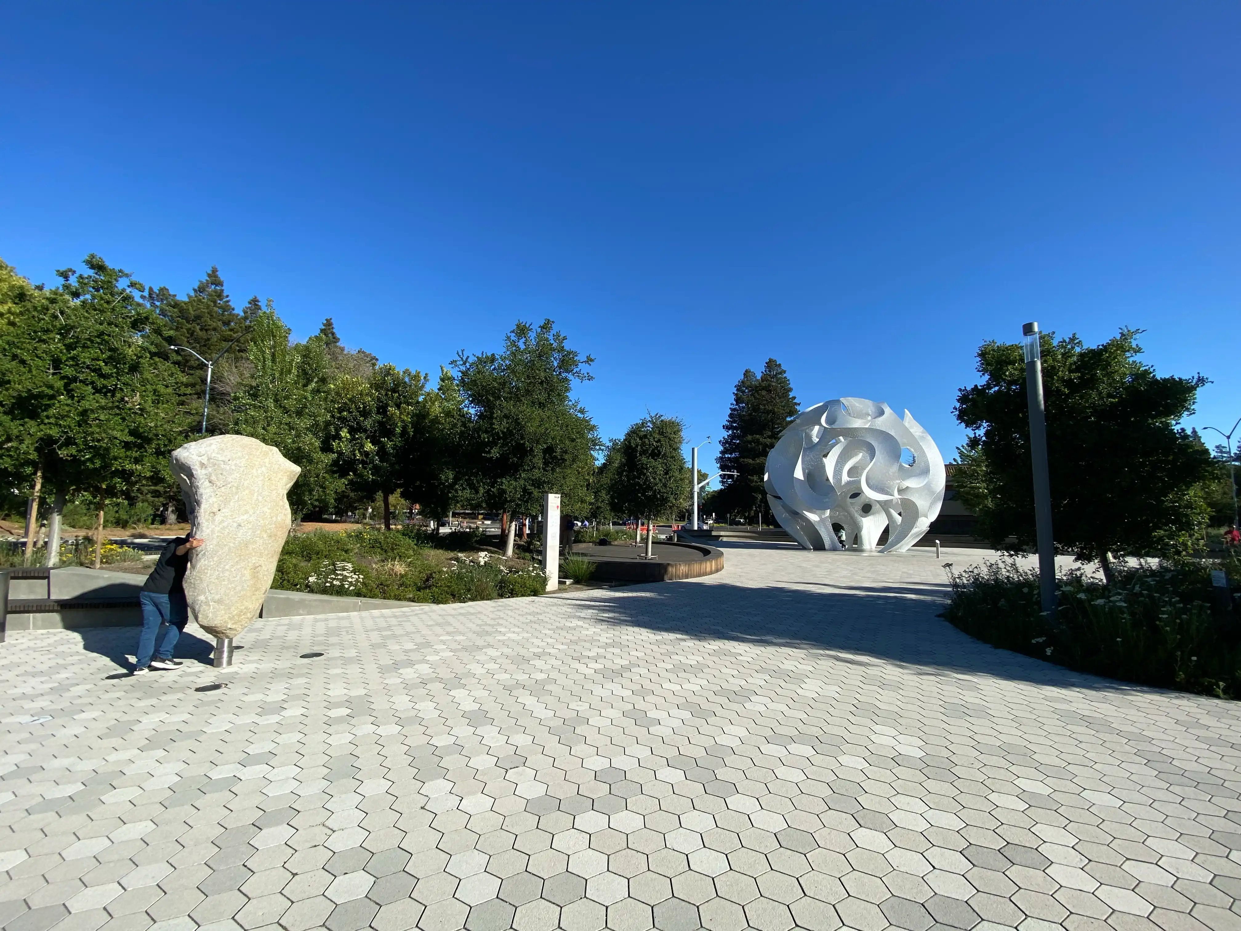 Inside the grounds, there's a large white art object and a rock object, with someone rotating the latter