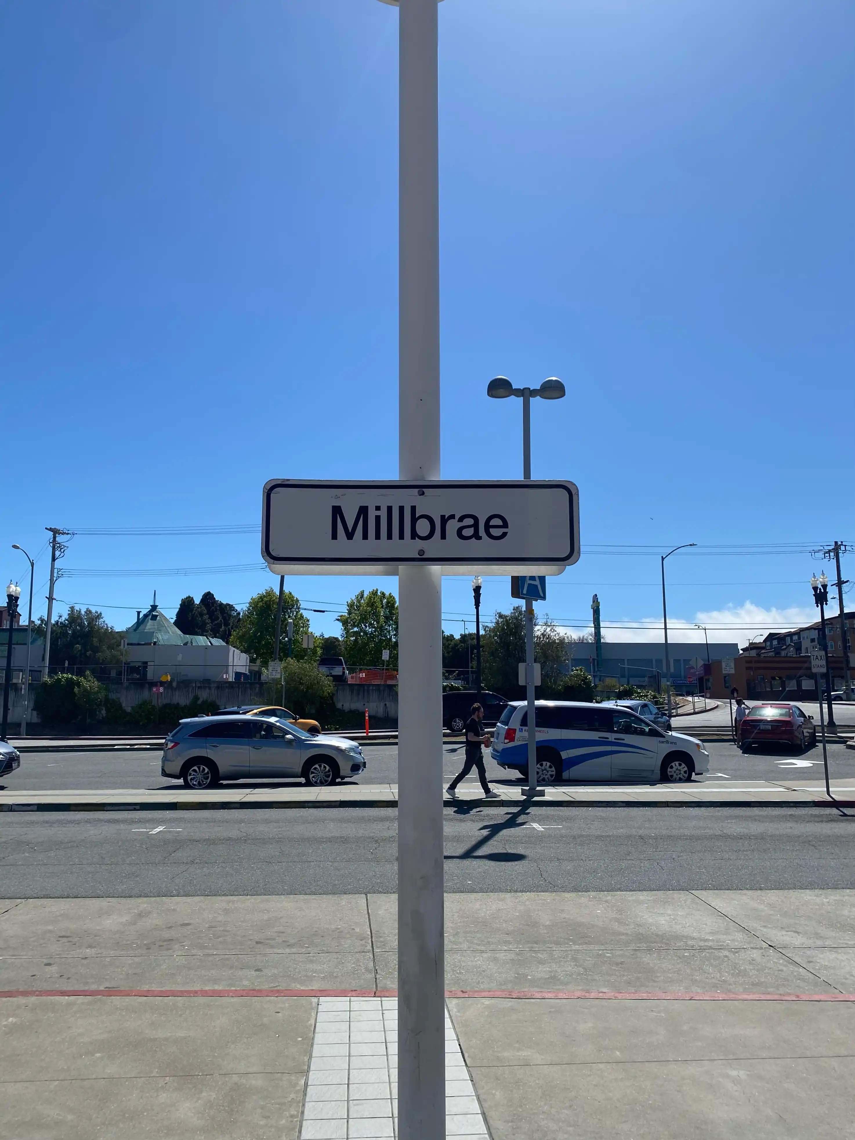 A sign with "Millbrae" written on it under a cloudless blue sky